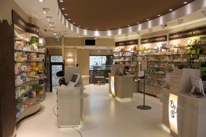 negozio farmacia stile moderno con casse e boiserie in laminato legno ed elementi d'arredo in cristallo e bronzo, design fc arredamenti